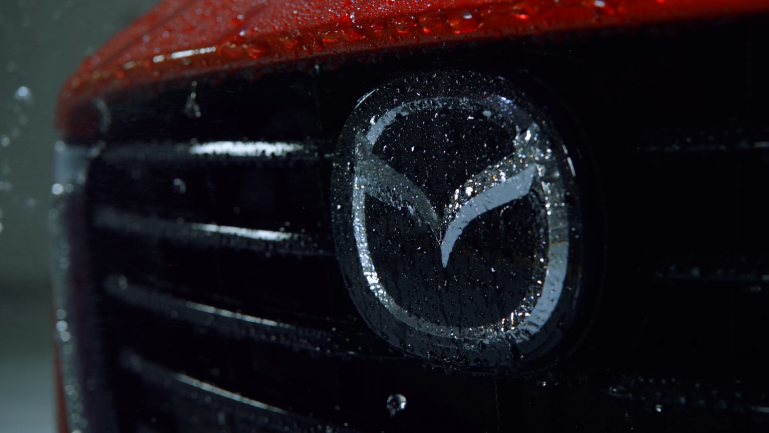 Shot of red Mazda, front grill and the Mazda emblem.