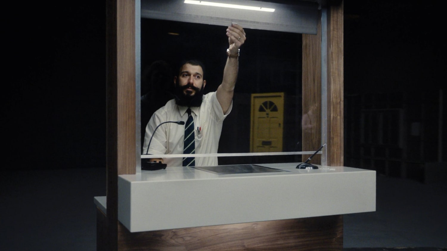 Man behind glass imitating a bank cashier
