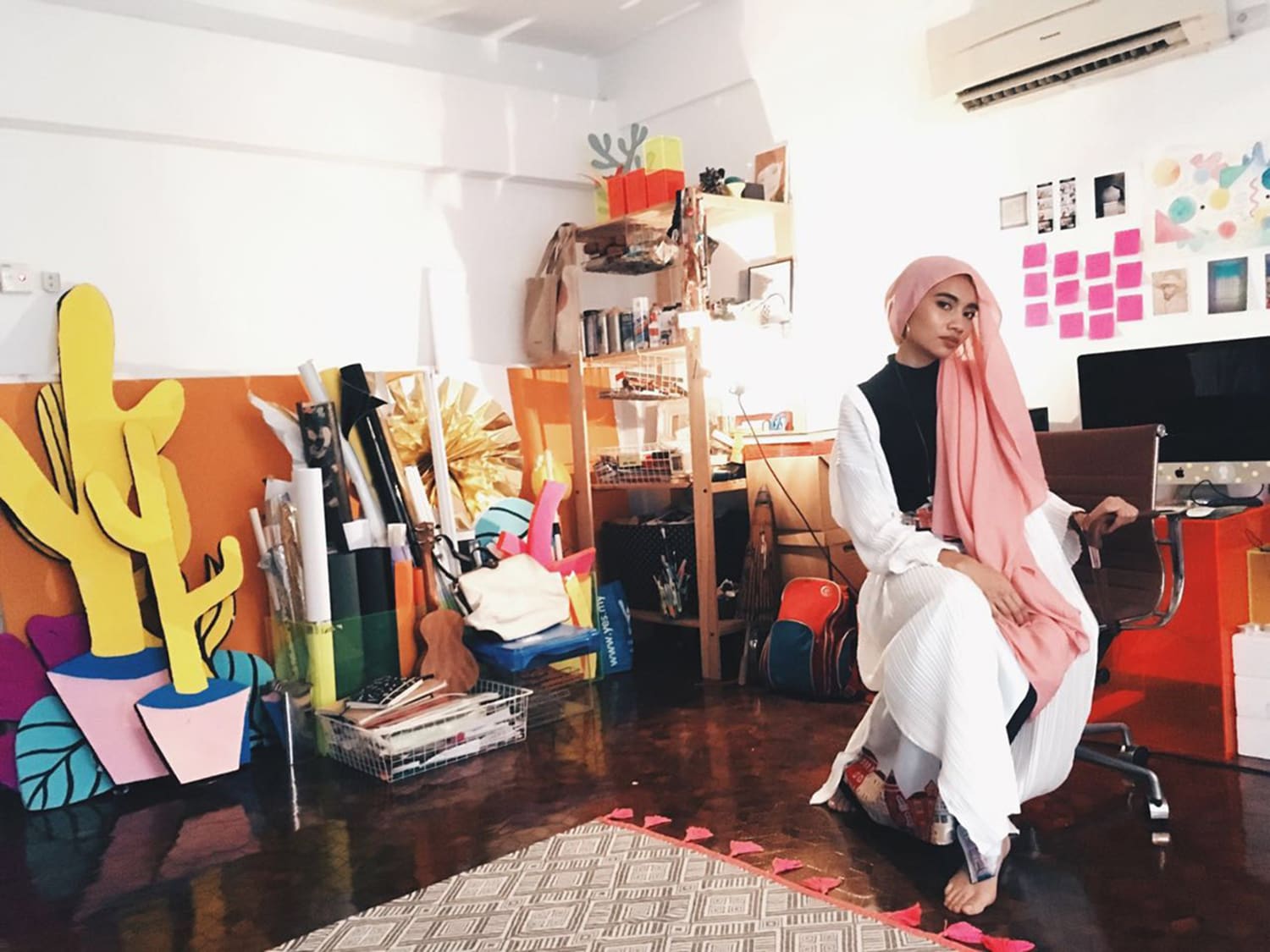 Malaysian pop singer songwriter Yuna sitting on a chair in her fashion studio