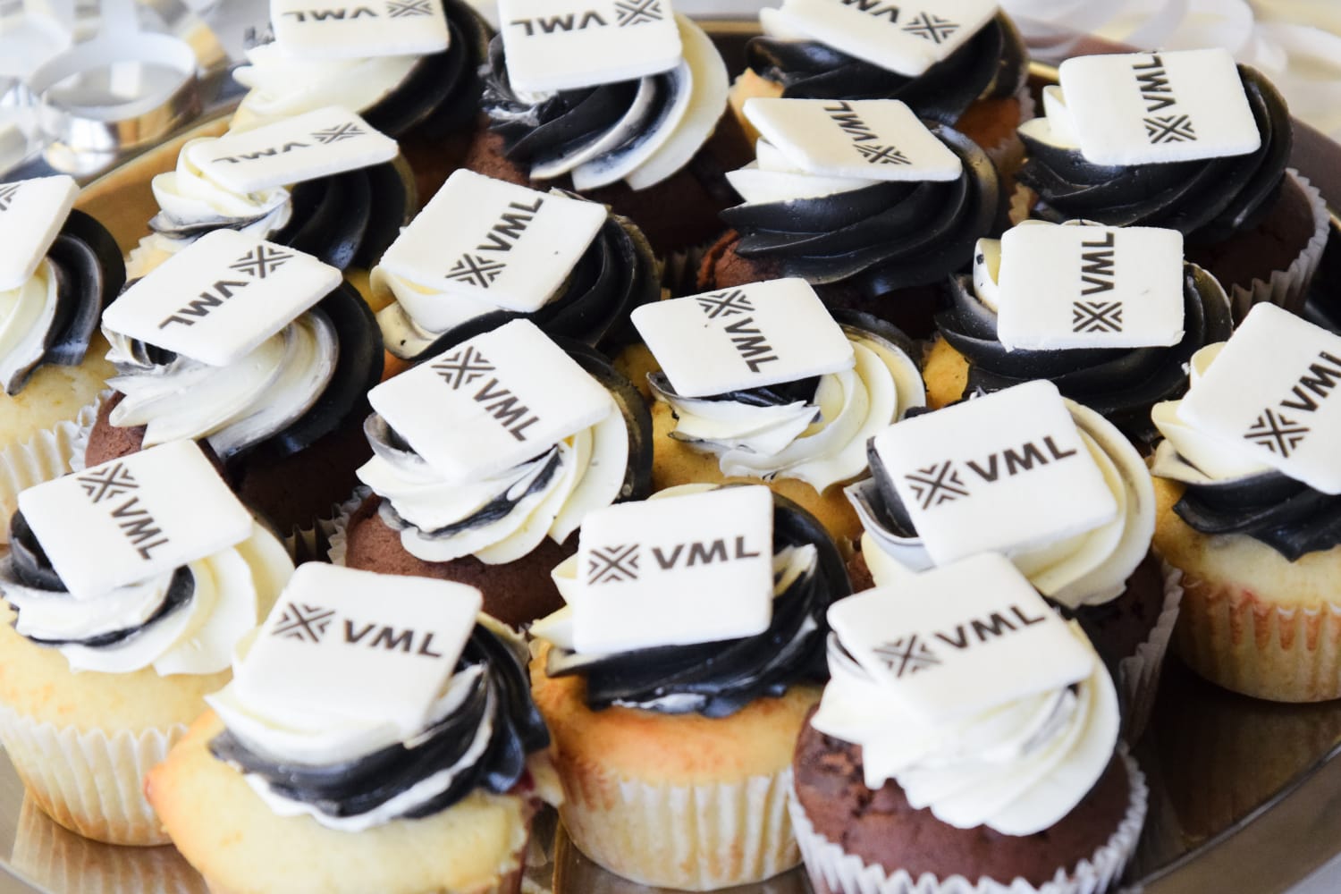 Picture of vanilla and chocolate cupcakes with an edible VML decoration on top