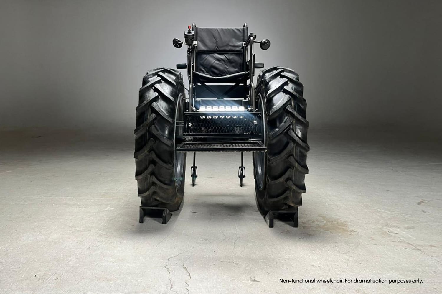 Una imponente vista trasera de la 'SILLA MONSTER' muestra sus colosales ruedas de tractor y su estructura robusta en un estudio, simbolizando la denuncia contra la falta de accesibilidad y el bloqueo de rampas en Argentina.