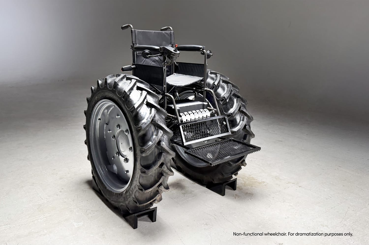 Una imponente vista trasera de la 'SILLA MONSTER' muestra sus colosales ruedas de tractor y su estructura robusta en un estudio, simbolizando la denuncia contra la falta de accesibilidad y el bloqueo de rampas en Argentina.