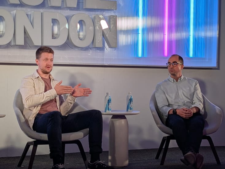 Two men on stage speaking at SXSW London, one gesticulates as the other listens.