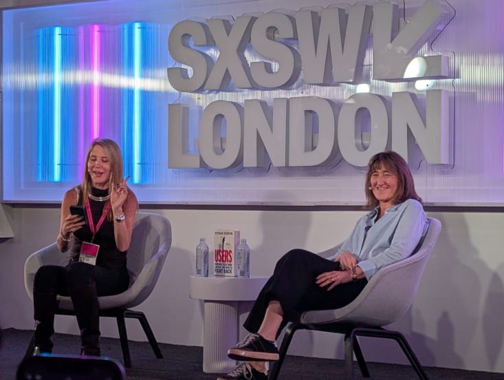Two women chat on stage in front of a SXSW London logo.