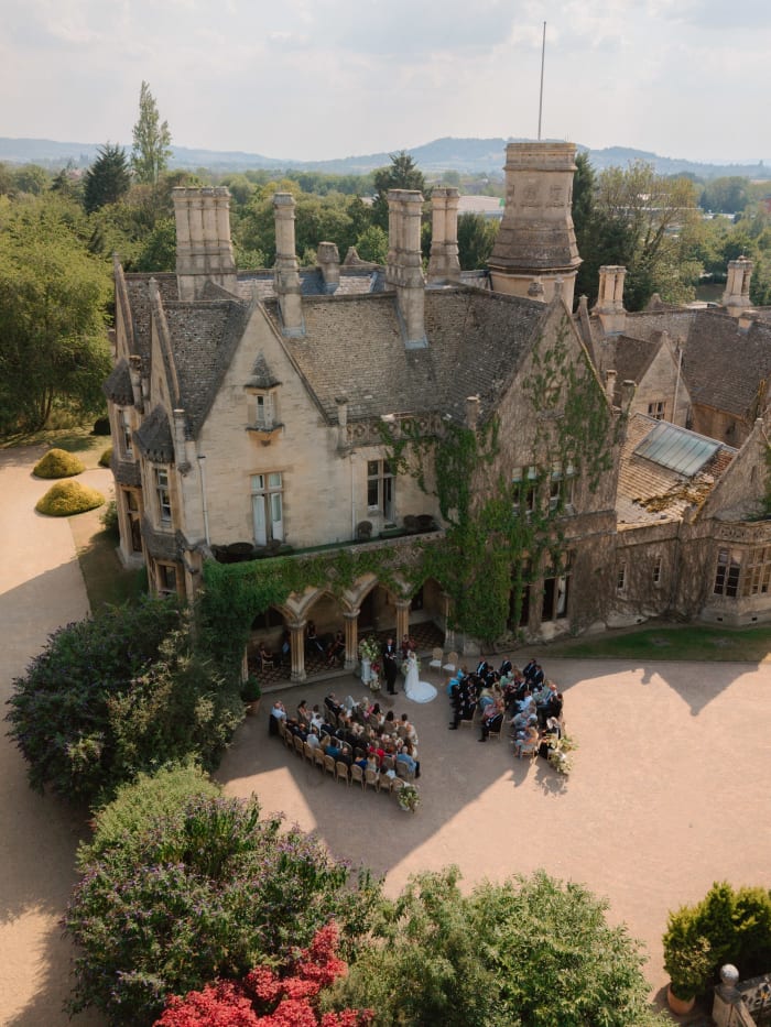 The manor house from the air with guests gathered for the ceremony below, The Cotswolds