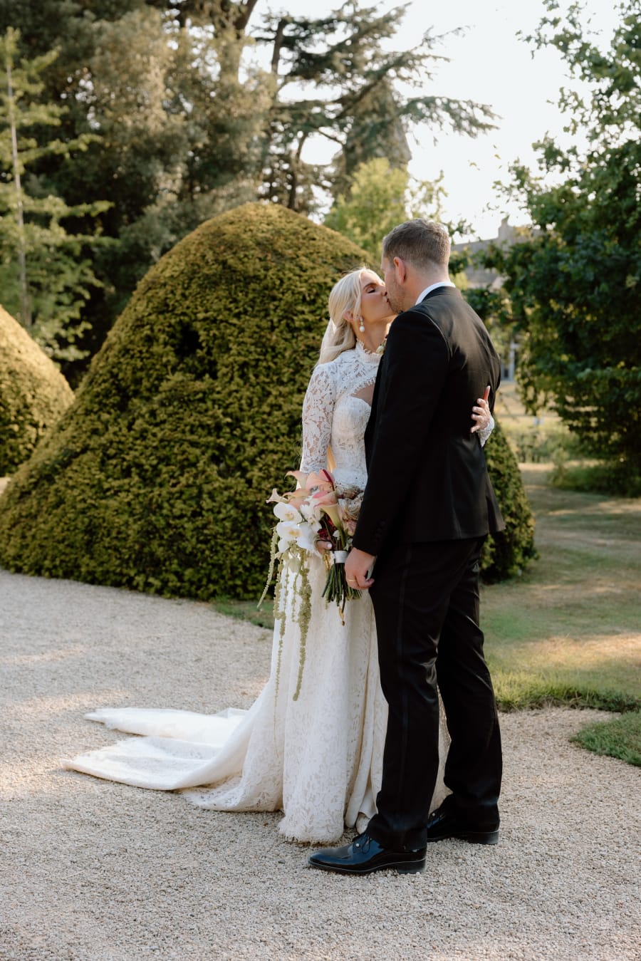 Morgan and Josh kissing beside the topiary in the gardens, The Cotswolds