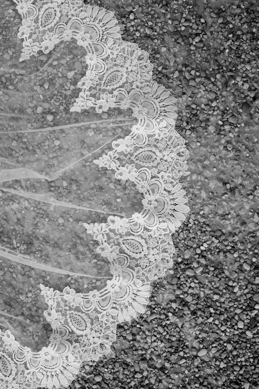 The lace edge of Morgan's veil spread across the gravel, in black and white, The Cotswolds