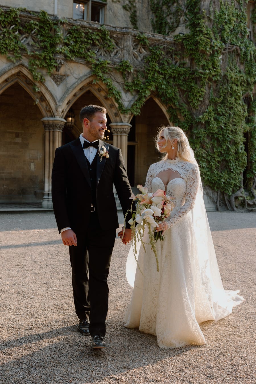Morgan and Josh walking together past the ivy-covered cloisters, The Cotswolds