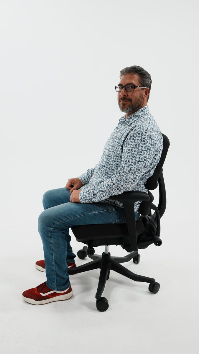 A person seated in the Anthros chair, pelvis supported in a neutral position, weight distributed evenly away from the tailbone.