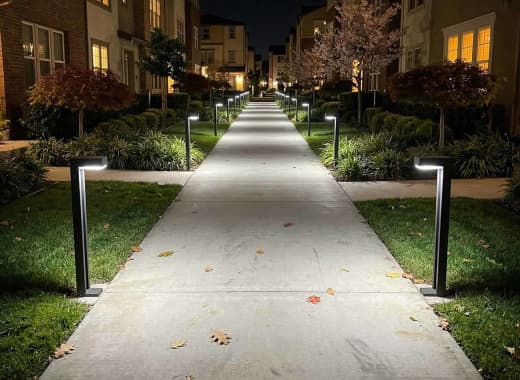 True Lumens™ solar bollard lights lining an HOA community entry walkway at night