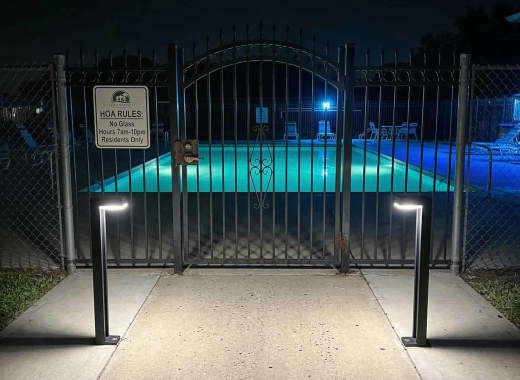 True Lumens™ solar bollard lights at an HOA community pool gate entrance at night