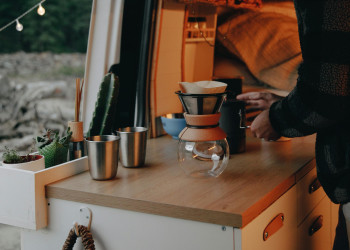 Man prepares coffee on counter inside his van pnw-prod-9354766.jpg