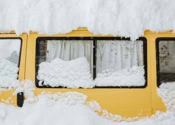 Heavy snow piled on top of a vintage yellow camper jorg-angeli-RA7o VghRtU.jpg