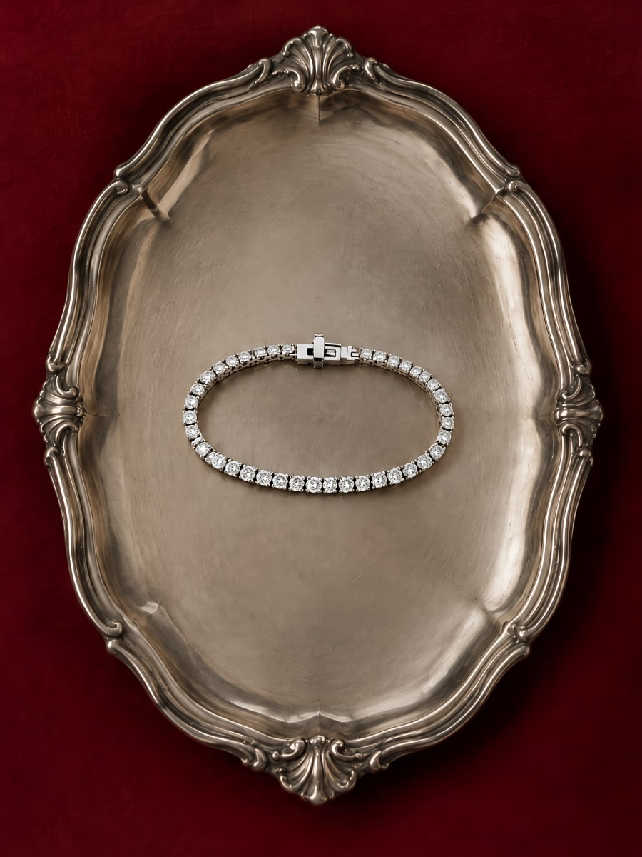 Diamond tennis bracelet on an antique silver tray, oxblood background