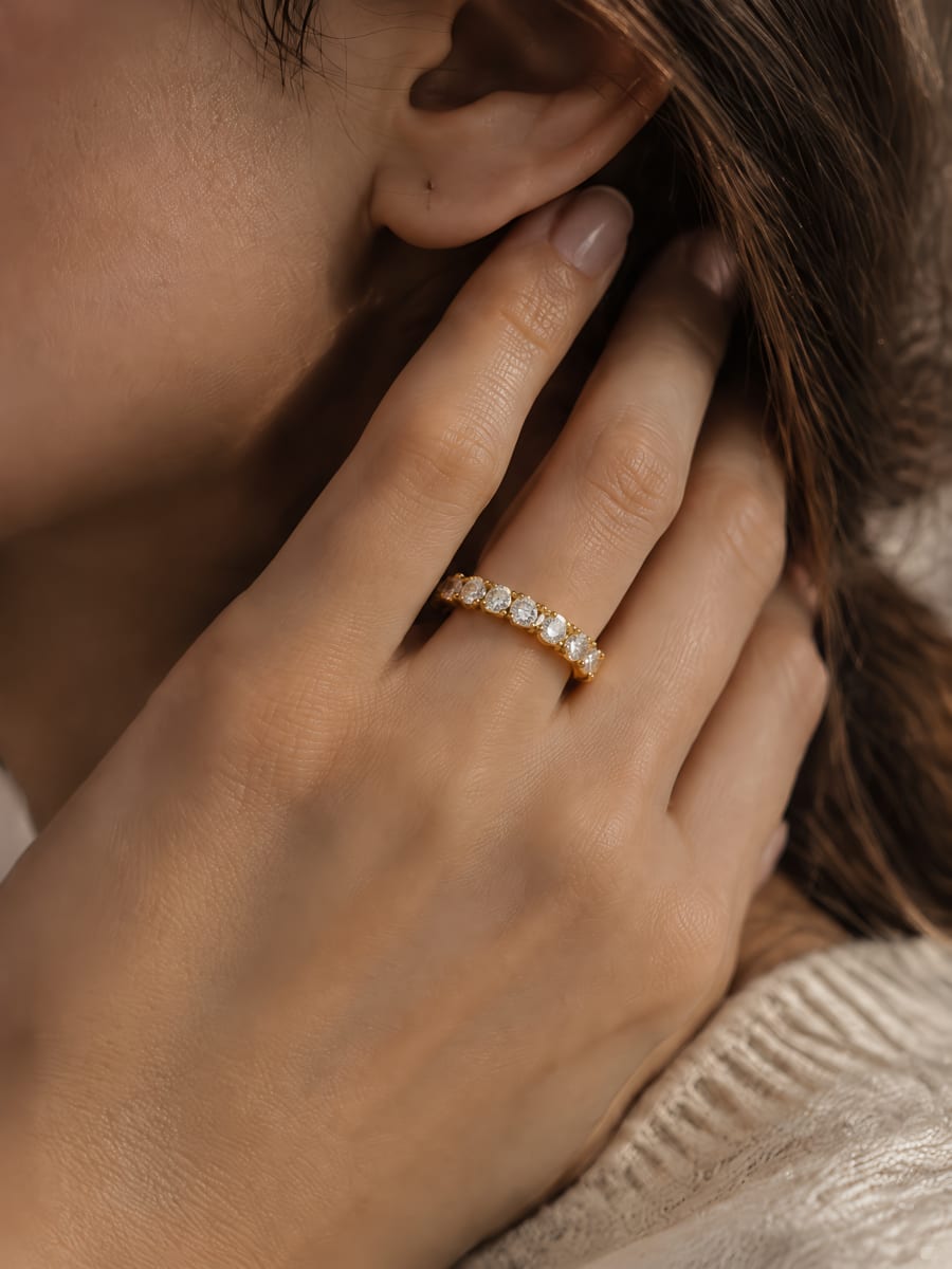 Gold diamond band worn on a hand touching the neck, close-up