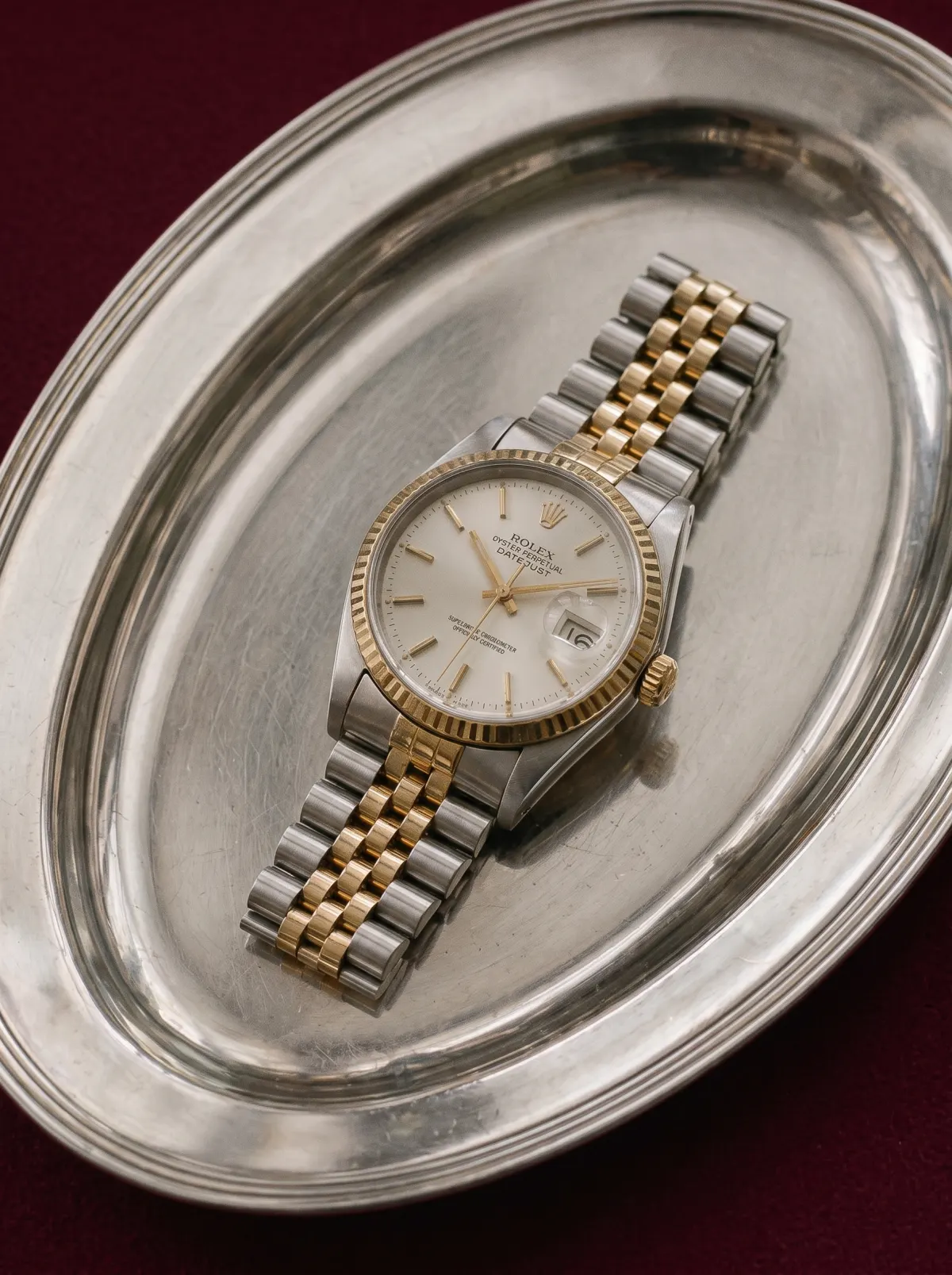 A two-tone steel and gold watch with a champagne dial on an oval silver tray, cleaned and ready for the shoot