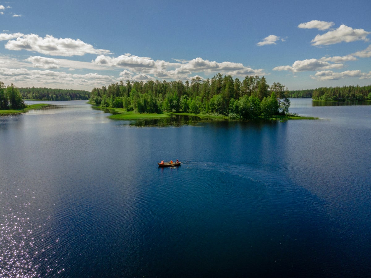 A small boat out on a calm forest lake near Levi under June summer skies