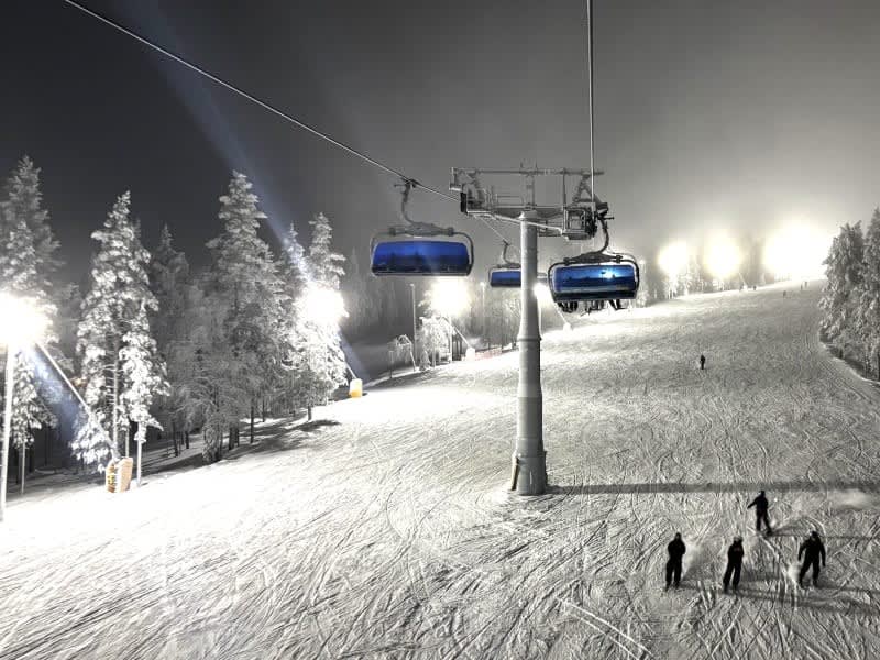 Chairlift above a floodlit piste at Levi on a winter evening