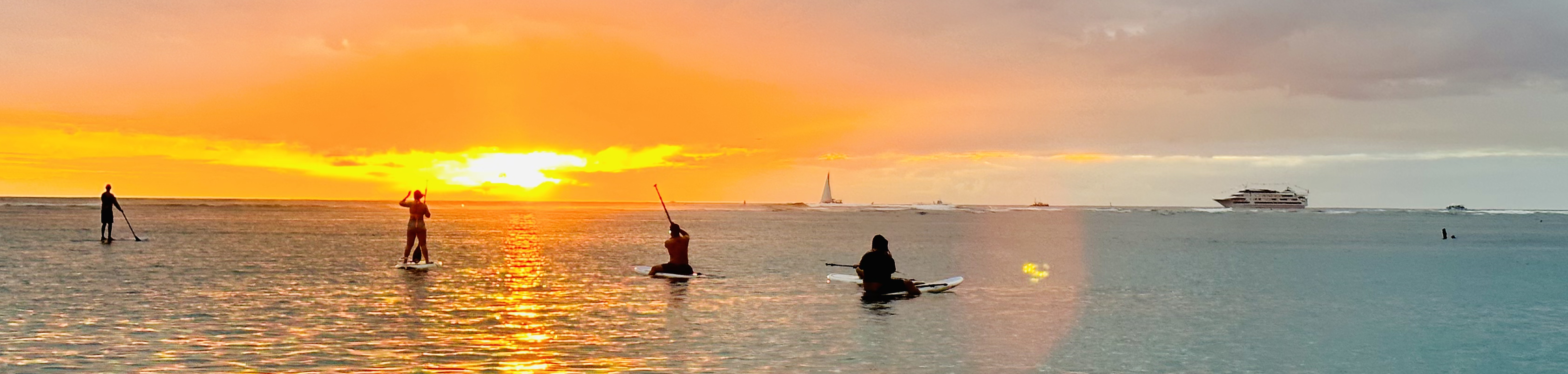 Sunset over Ala Moana Beach Park with paddleboarders on the water