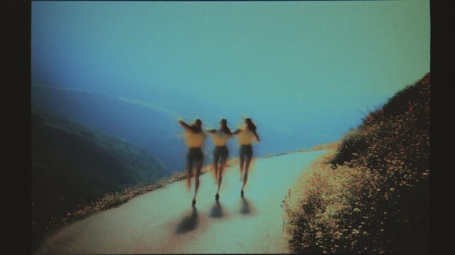 Three figures running along a coastal path in a faded film-photo look