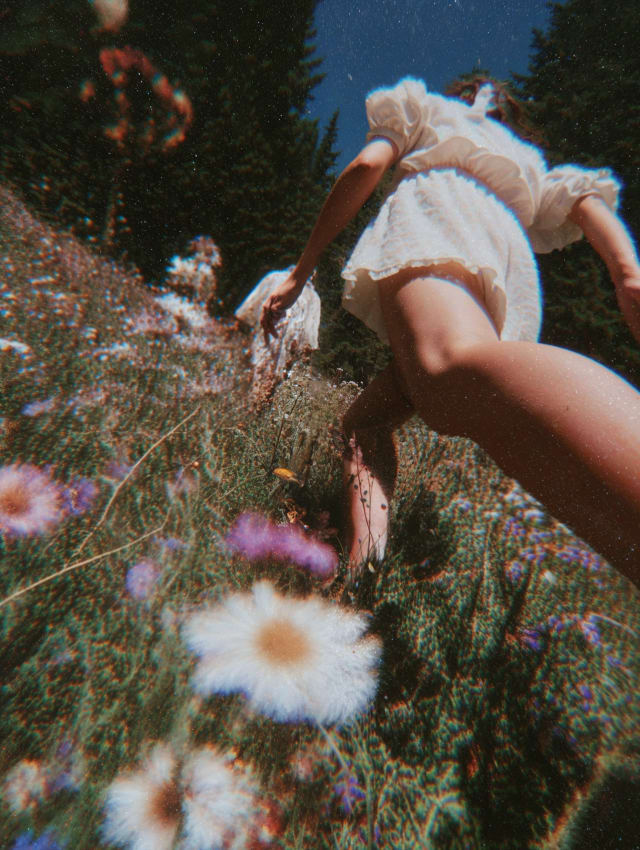 Barefoot legs of someone in white lace shorts running through a wildflower meadow