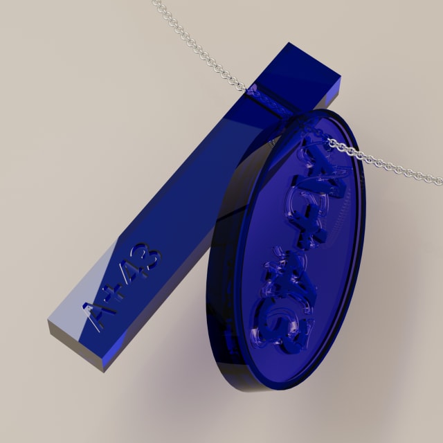 Blue glass bar and oval pendant with engraved lettering hanging on a silver chain against a pale wall