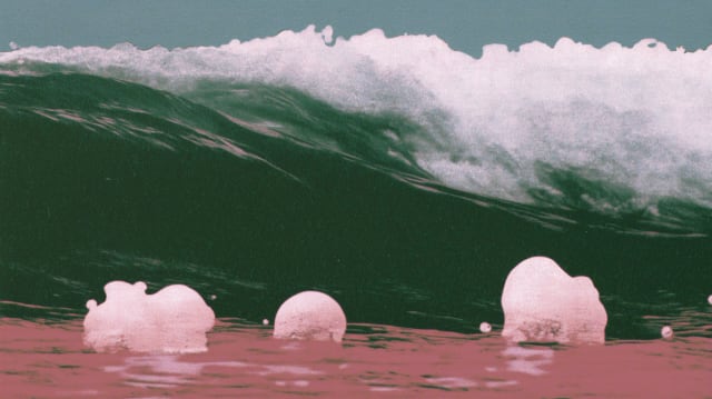 Green wave breaking over a pink sea with soft pink blobs in the foreground