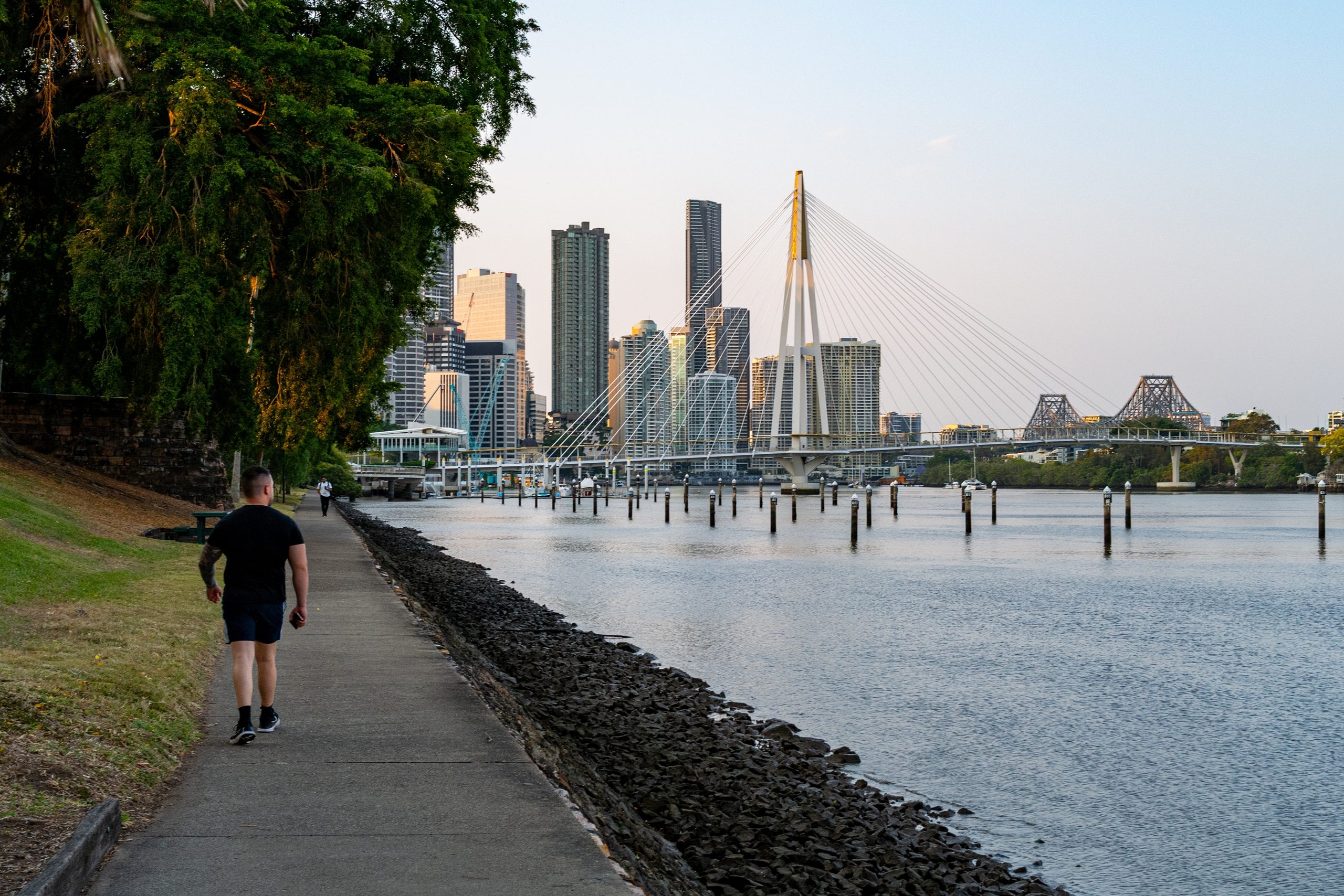 People walking the City Botanic Gardens riverwalk toward the Story Bridge