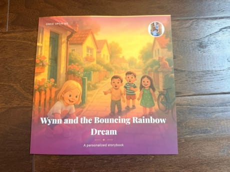 Front cover of a real printed personalized softcover storybook, 'Wynn and the Bouncing Rainbow Dream', with the child's photo on the cover