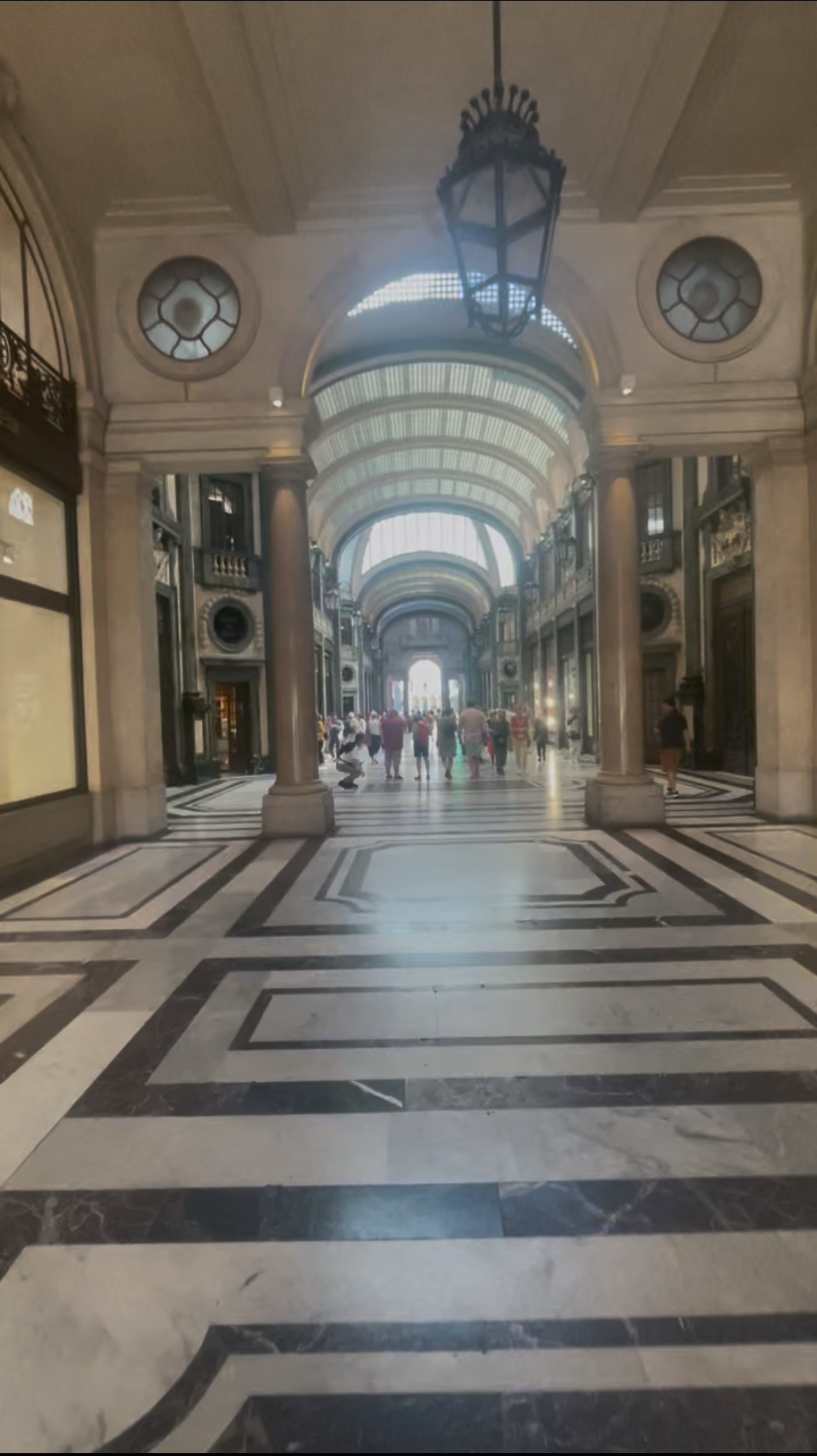 The grand covered arcade in Turin – black and white marble floors, ornate arched glass ceiling, iron lanterns, elegant 19th-century architecture