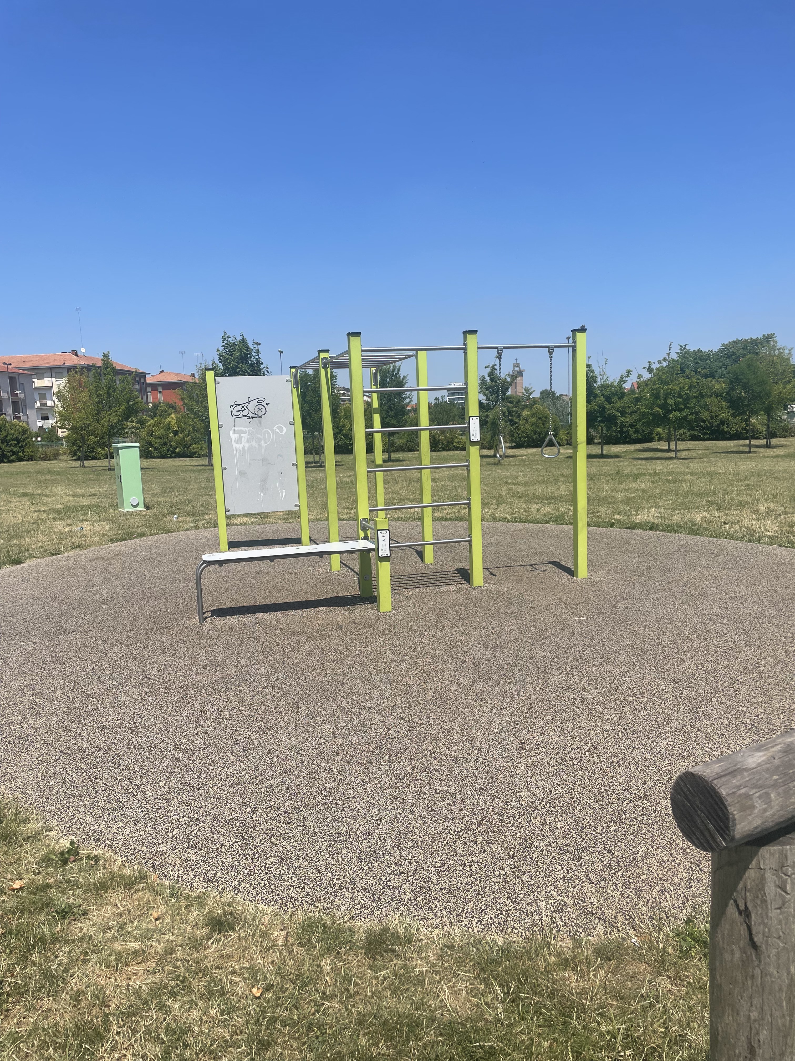 Outdoor calisthenics park in the Po Valley – yellow-green pull-up bars and rings under a deep blue Italian sky