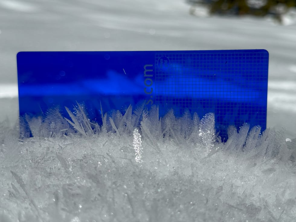 surface hoar crystals against a blue measurement grid.