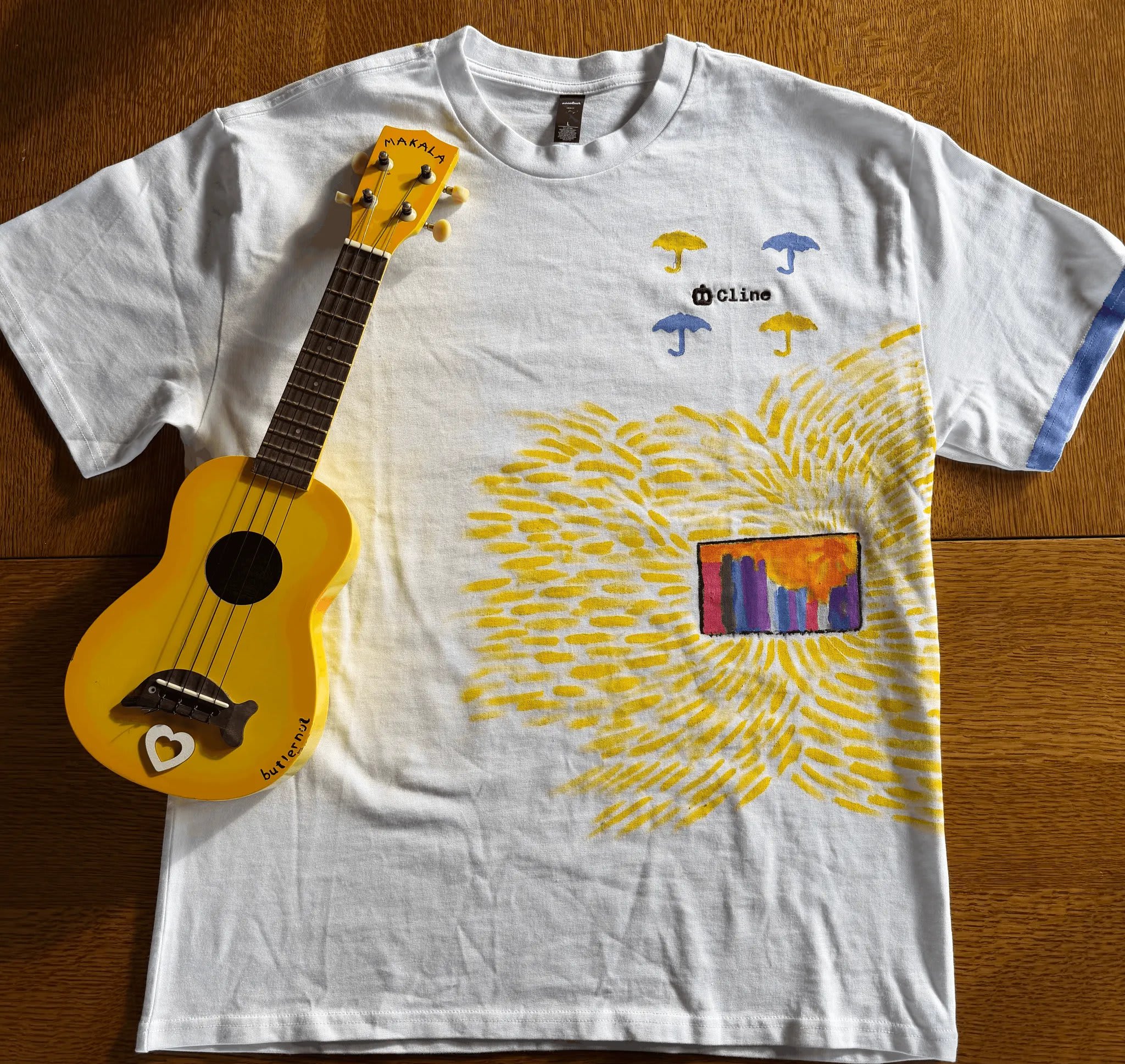 Grey t-shirt with sunshine, guitars, and umbrellas