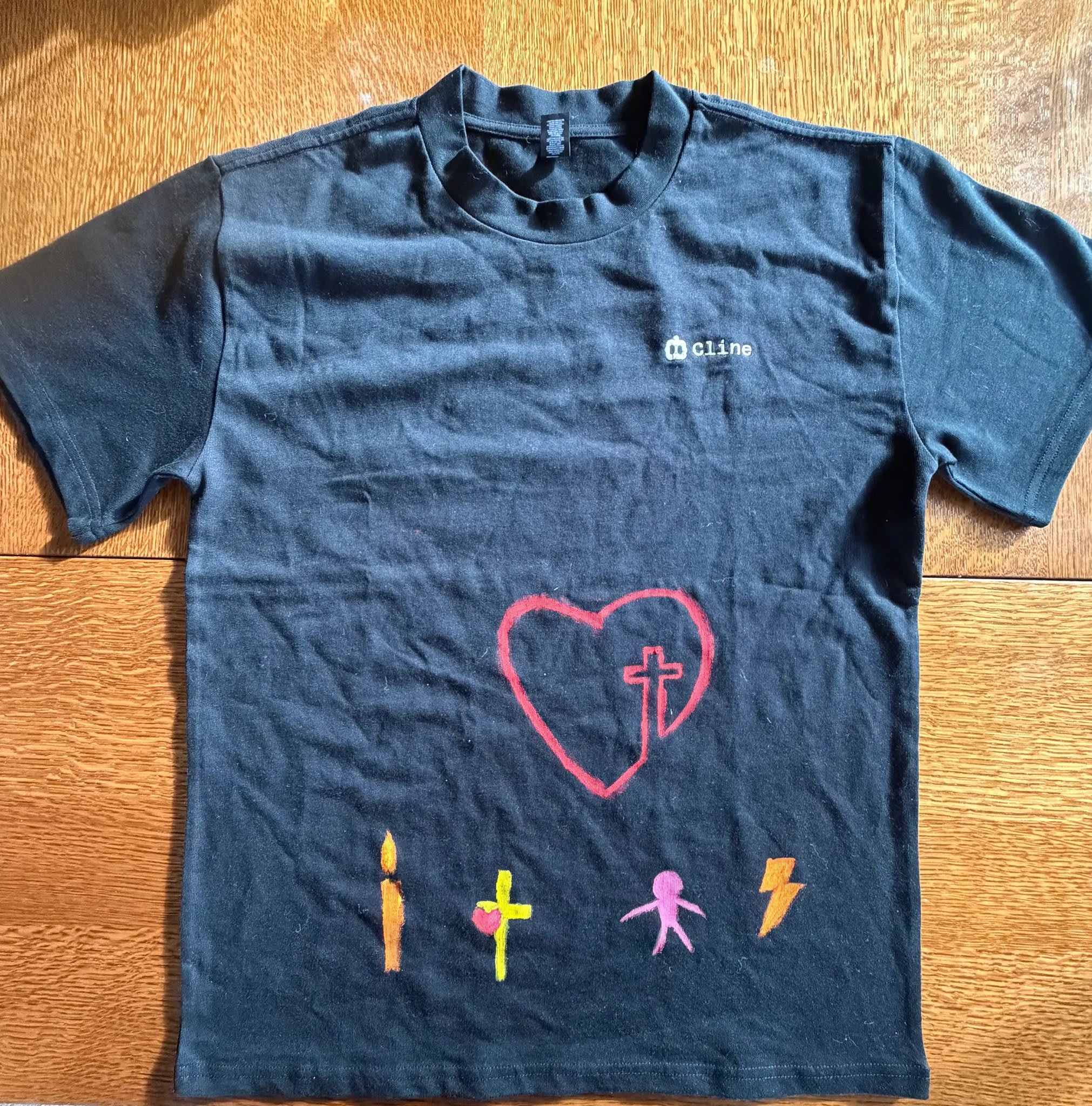 A contemplative design on black: a heart with a cross inside, a candle, a human figure, and a lightning bolt