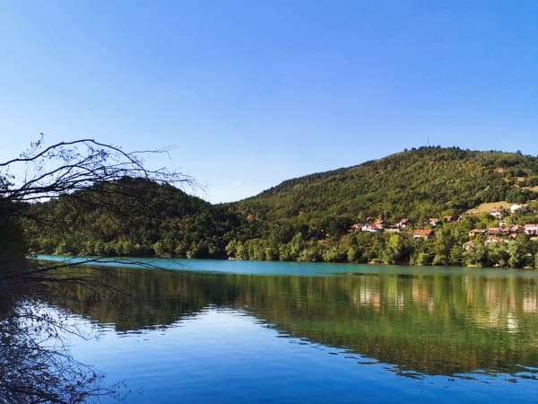 Bovansko jezero sa zelenim brdima i selom u pozadini