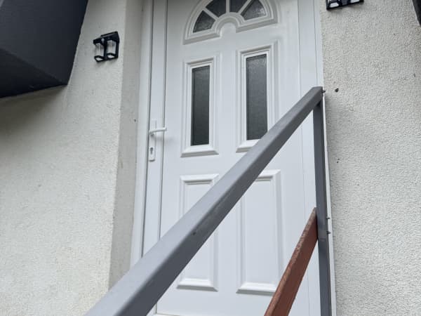 Bela ulazni vrata apartmana sa staklenim panelima i zidnim lampama