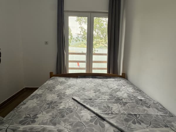 Spavaća soba sa bračnim krevetom i pogledom na prirodu kroz balkonska vrata