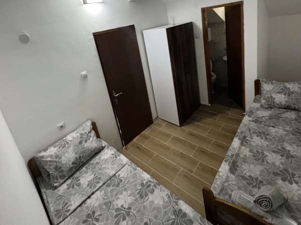 Soba sa dva jedno kreveta, sivim posteljinom i pogledom na kupatilo