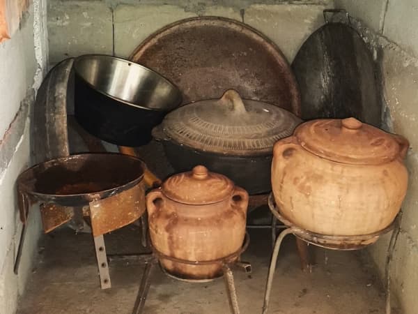 Tradicionalni glineni lonci i sač u niši kamene peći za roštilj