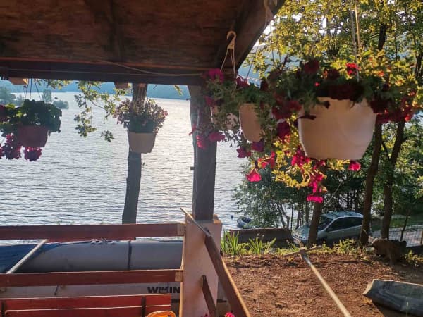 Pokrivena terasa sa visećim cvećem i pogledom na jezero