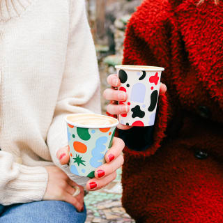 Two people holding patterned paper cups