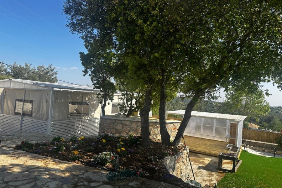 שביל אבן וערוגות פרחים בין העצים בחצר הווילה בנס הרים