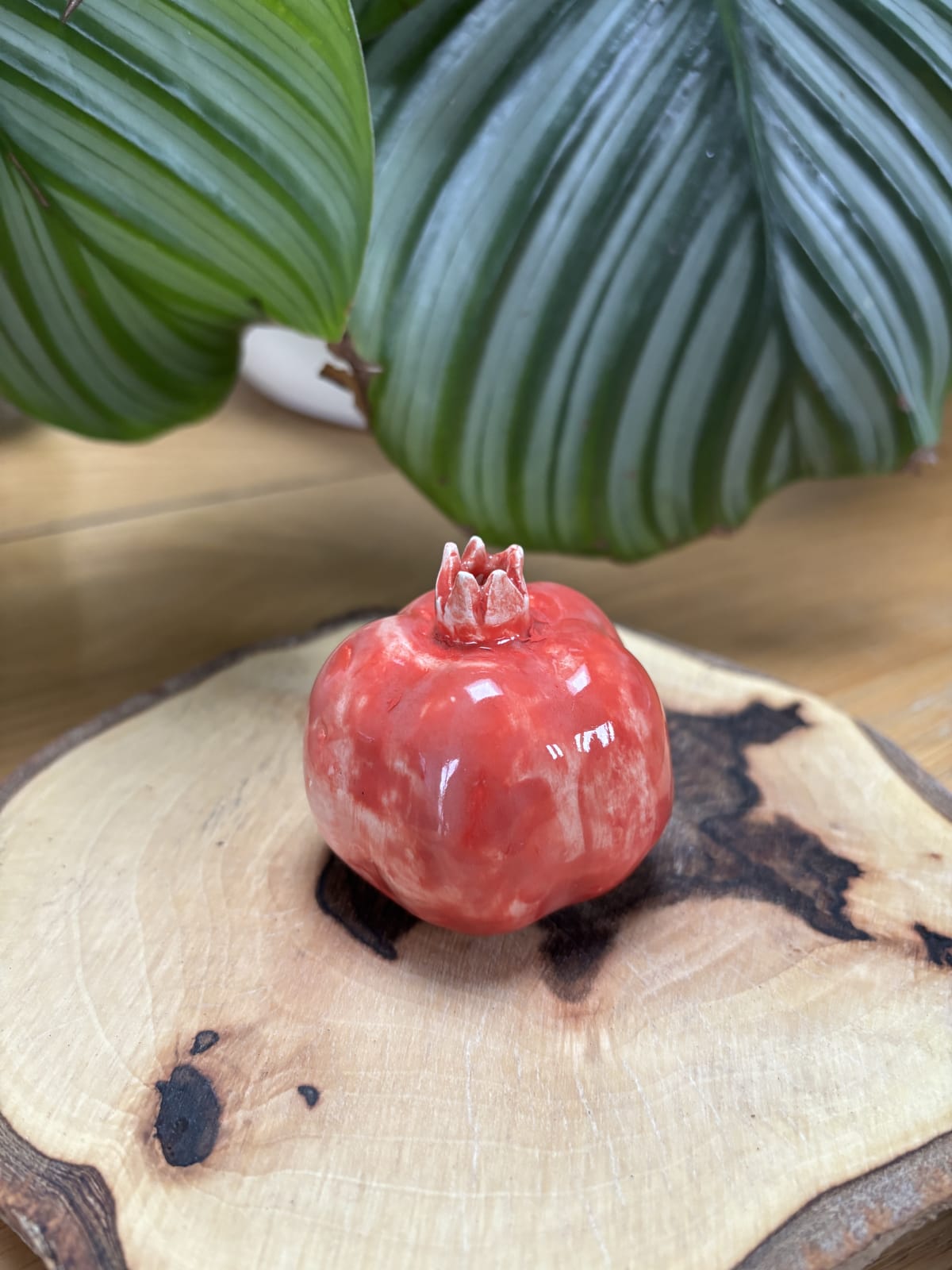 A handmade coral-red ceramic pomegranate from InchyArt, a symbol of love, abundance and new beginnings