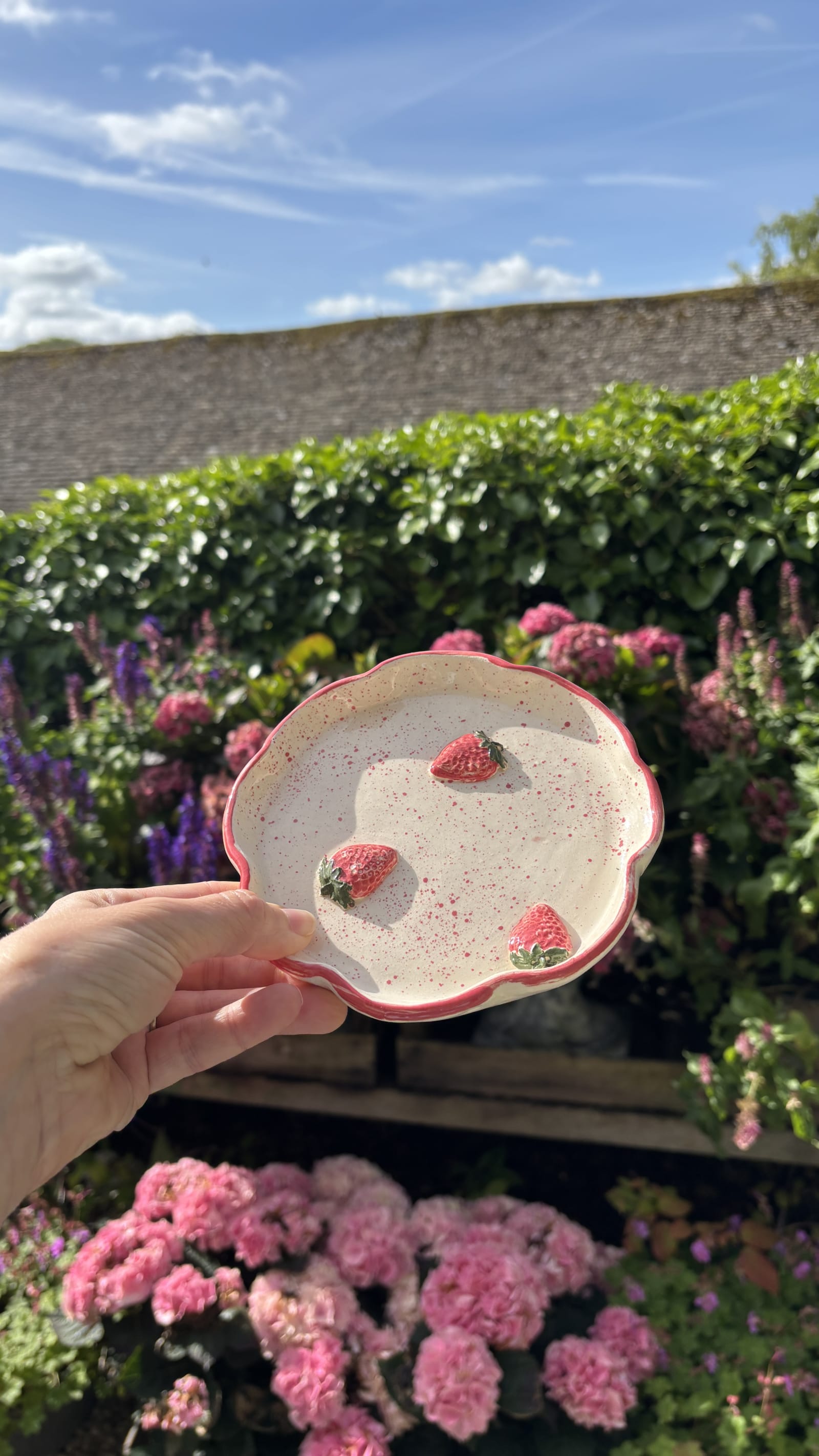Round ceramic trinket dish with three sculpted strawberries, pink speckled finish, and scalloped edge, 15cm diameter