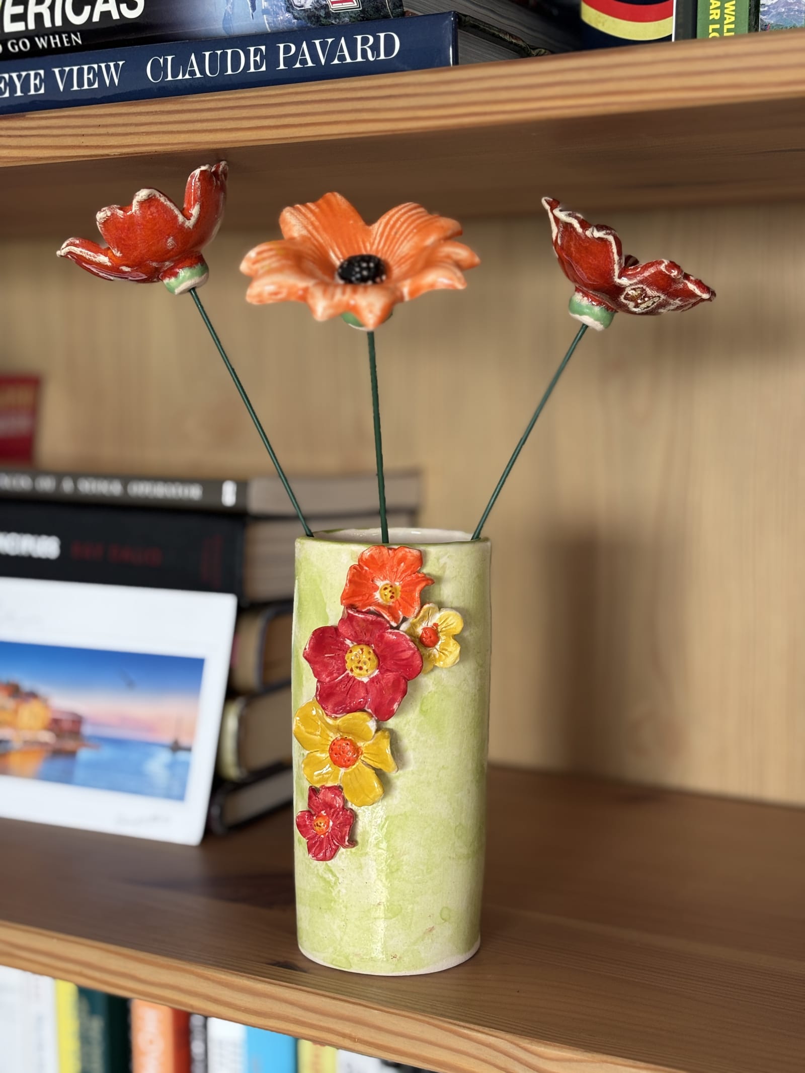 Green ceramic vase covered in colourful hand-sculpted flowers in red, orange, and yellow, 15cm tall