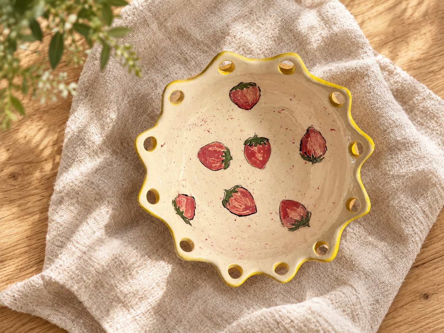 Handmade cream ceramic bowl with painted strawberries and a yellow scalloped rim.