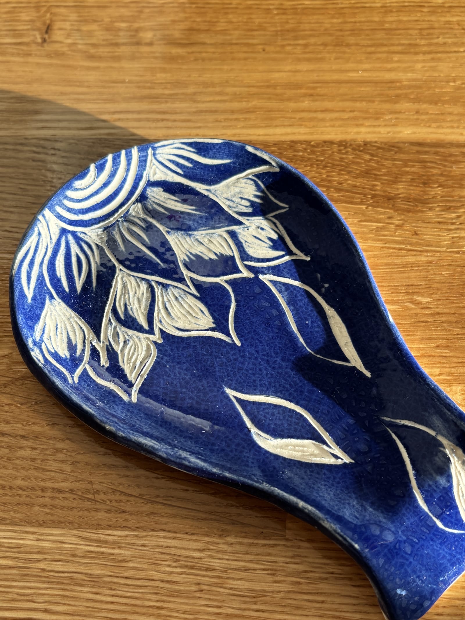 Handmade blue floral ceramic spoon rest with cream botanical leaf and flower design