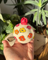 Close-up of the hand-painted floral design on the ceramic pomegranate surface