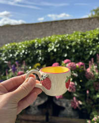 Mini ceramic espresso cup with hand-painted red strawberry pattern and bright yellow glazed interior