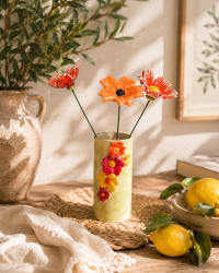Green ceramic vase covered in colourful hand-sculpted flowers in red, orange, and yellow, 15cm tall
